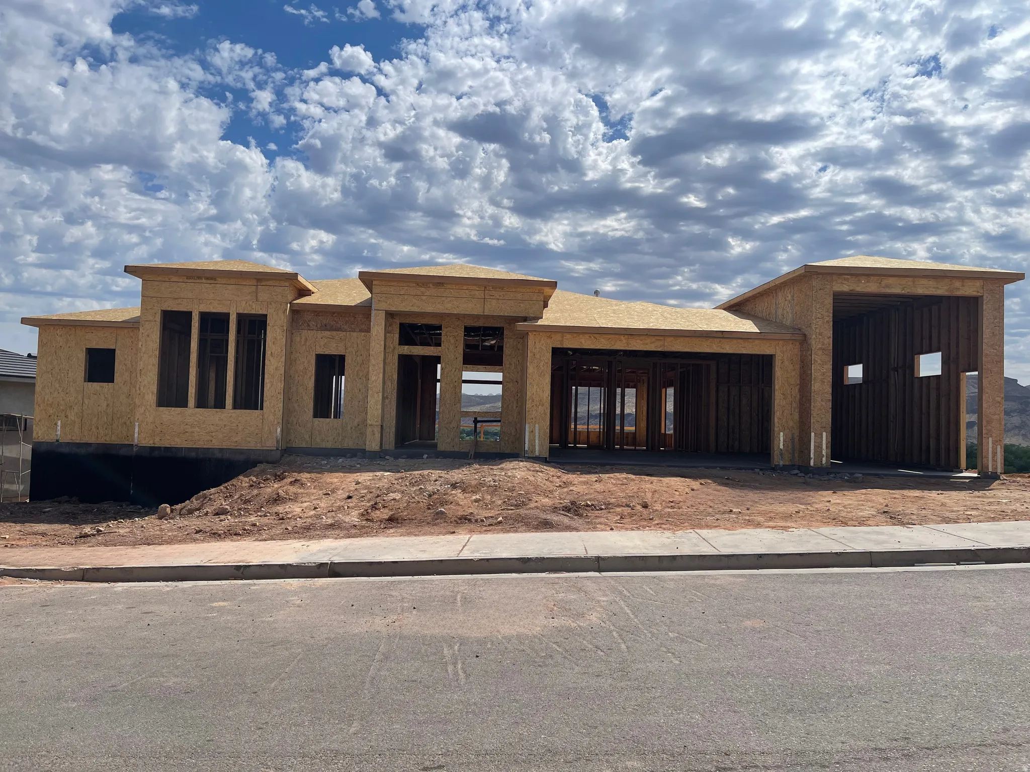 Contemporary architectural design featuring a prominent garage structure, multiple window openings, and an unfinished exterior