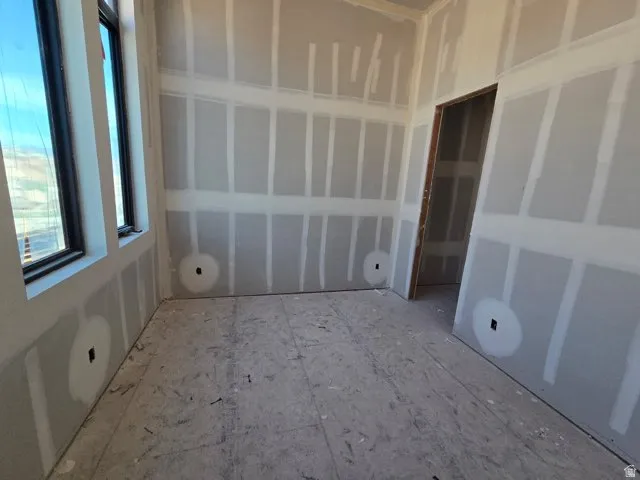 New construction interior with dual windows, drywall installation, and an unfinished wood subfloor