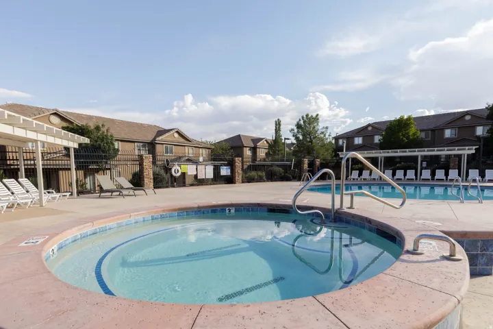 Outdoor spa with a blue tile border, adjacent to a large swimming pool