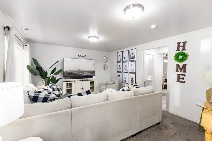 Spacious living area featuring neutral wall tones and plush carpet flooring
