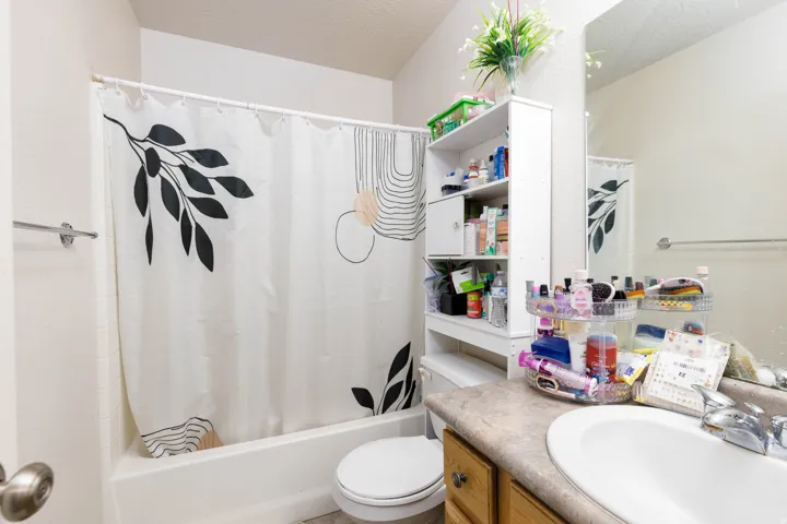 Bathroom featuring a white bathtub, a single vanity with an integrated sink, a light-toned countertop, and a wall-mounted mirror