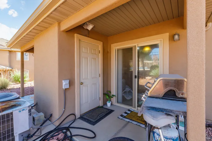 Covered patio featuring stucco exterior, concrete flooring, exterior lighting fixtures, and a sliding glass door