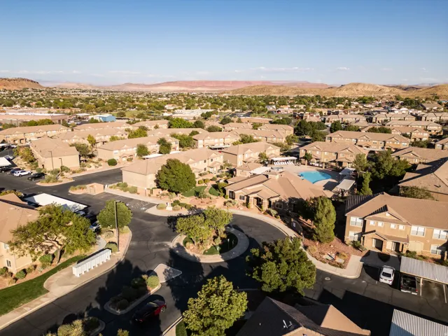Aerial perspective showcasing a residential community with numerous buildings, a central swimming pool, and dedicated parking areas
