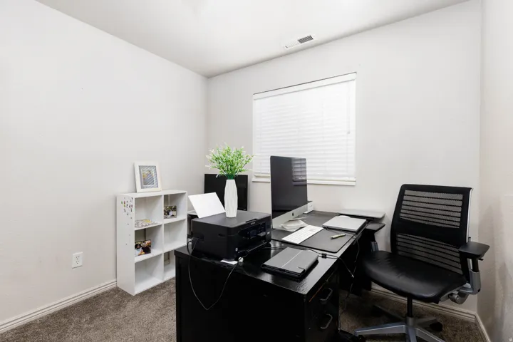 Carpeted room with neutral wall tones and a window featuring horizontal blinds