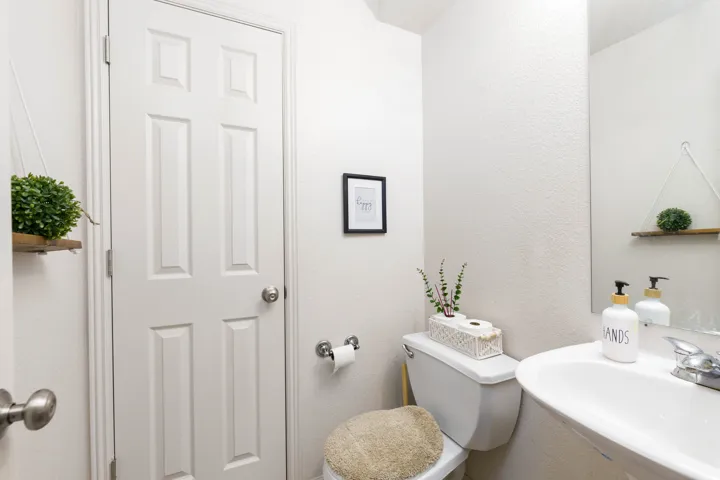 Compact bathroom featuring a pedestal sink with a chrome faucet, a white toilet, and a framed mirror