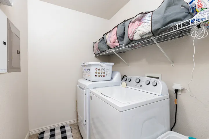 Dedicated laundry area featuring tile flooring and an overhead wire shelving unit