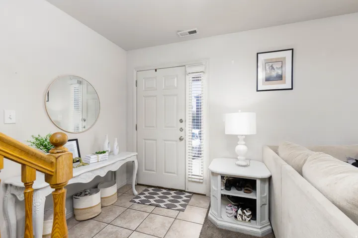 Foyer featuring a paneled entry door with sidelight, light tile flooring, and wood stair railing