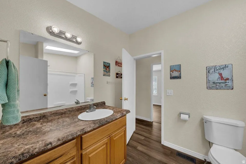 Bathroom featuring a vanity with a laminate countertop, an undermount sink, and wood cabinetry