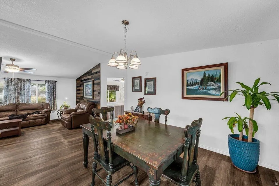 Open-concept living space with wood-finish flooring, a contemporary ceiling fan, and a rustic wood accent wall