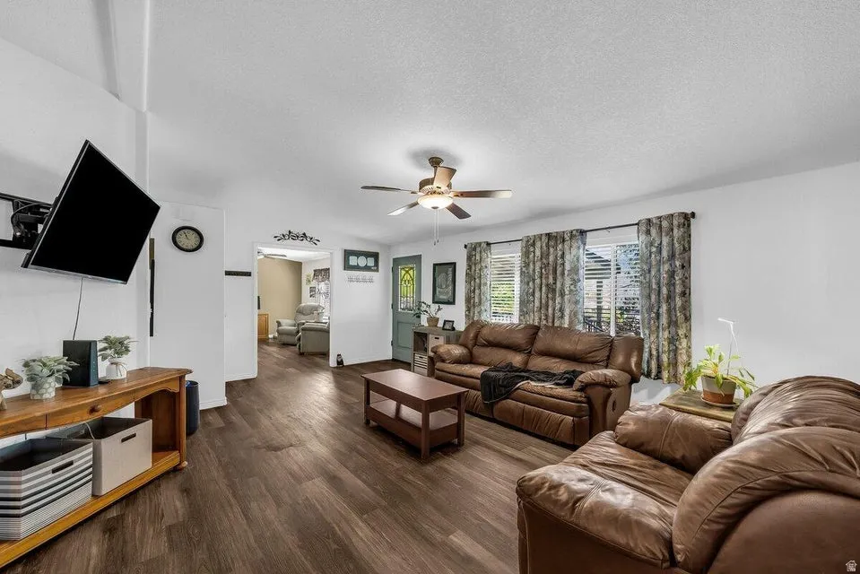 Living area featuring wood-finish flooring, white walls, and a ceiling fan