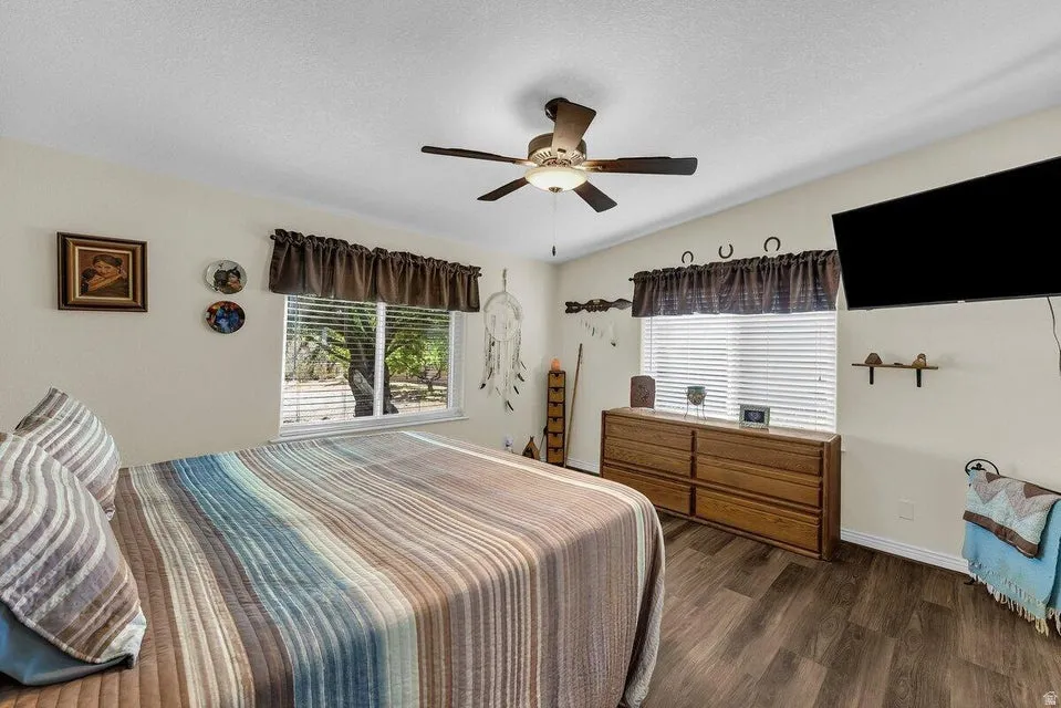 Interior space featuring wood-finish flooring, a ceiling fan with integrated lighting, and multiple windows with blinds for controlled illumination