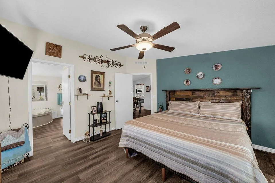 Bedroom featuring wood-finish flooring, a ceiling fan with integrated lighting, and direct access to an adjoining bathroom with a built-in tub