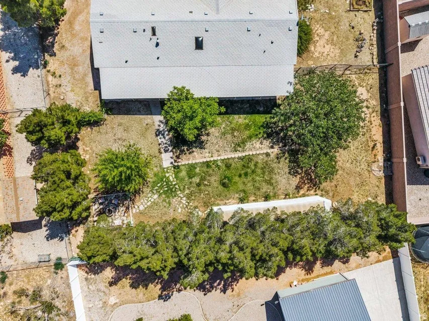 Expansive property featuring a central residence with a light-colored roof, mature trees, and natural landscaping