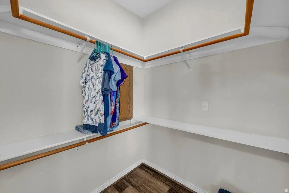 Walk-in closet with wood-finish flooring, white baseboards, and built-in white shelving