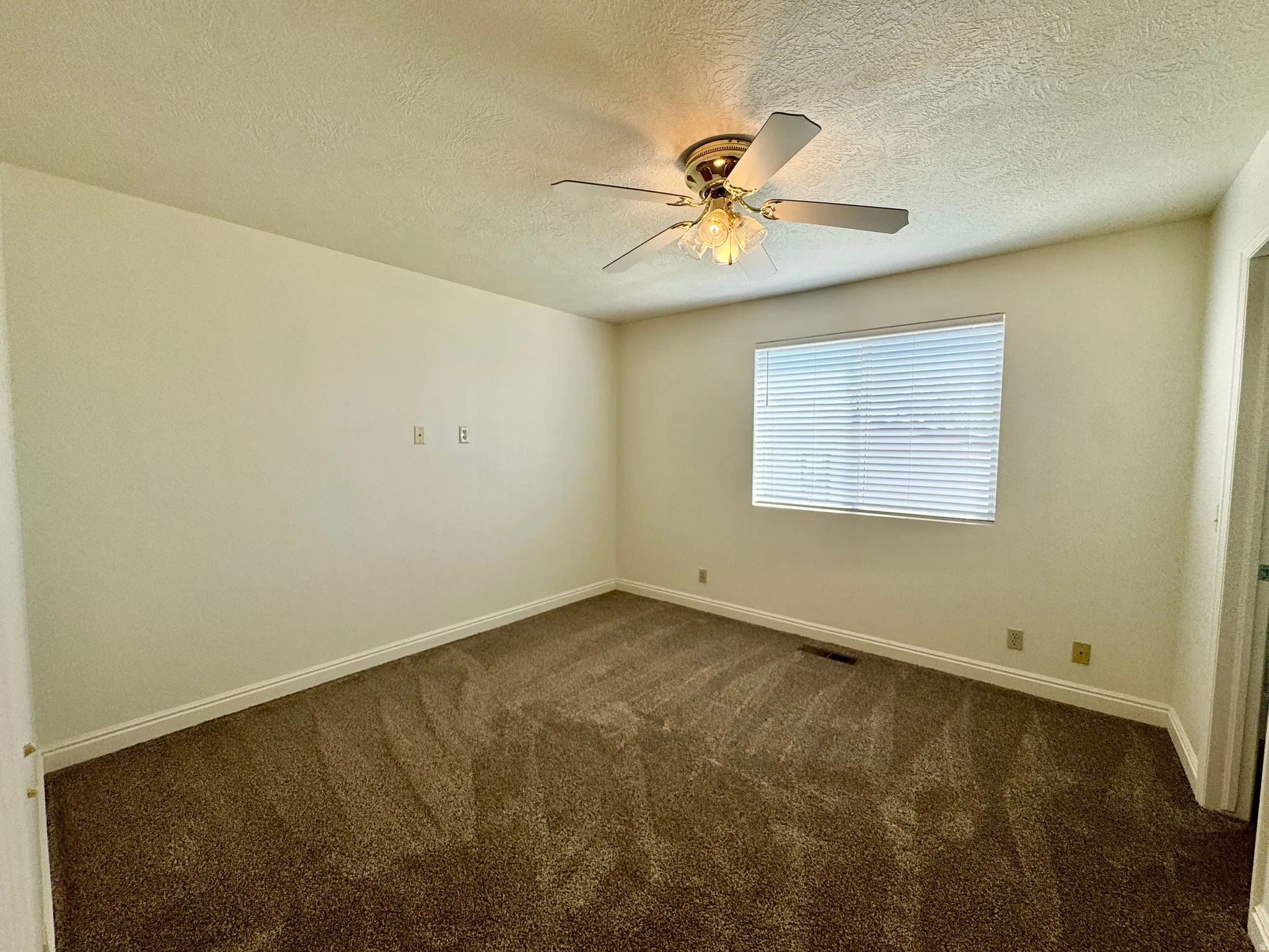 Room featuring wall-to-wall brown carpet, a ceiling fan with integrated lighting, and a single window with horizontal blinds