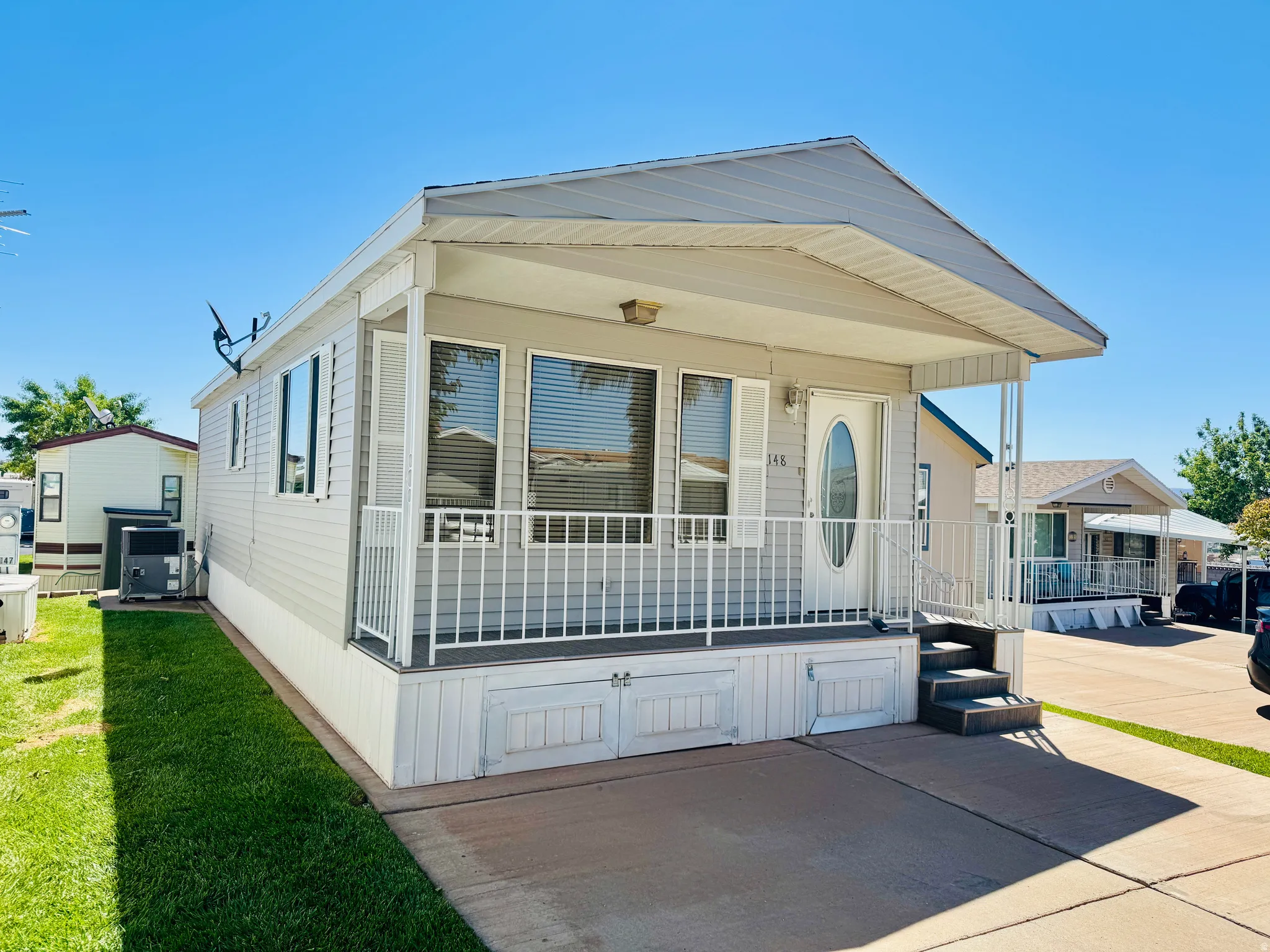 Manufactured home with covered front porch, white siding, and a partial privacy fence