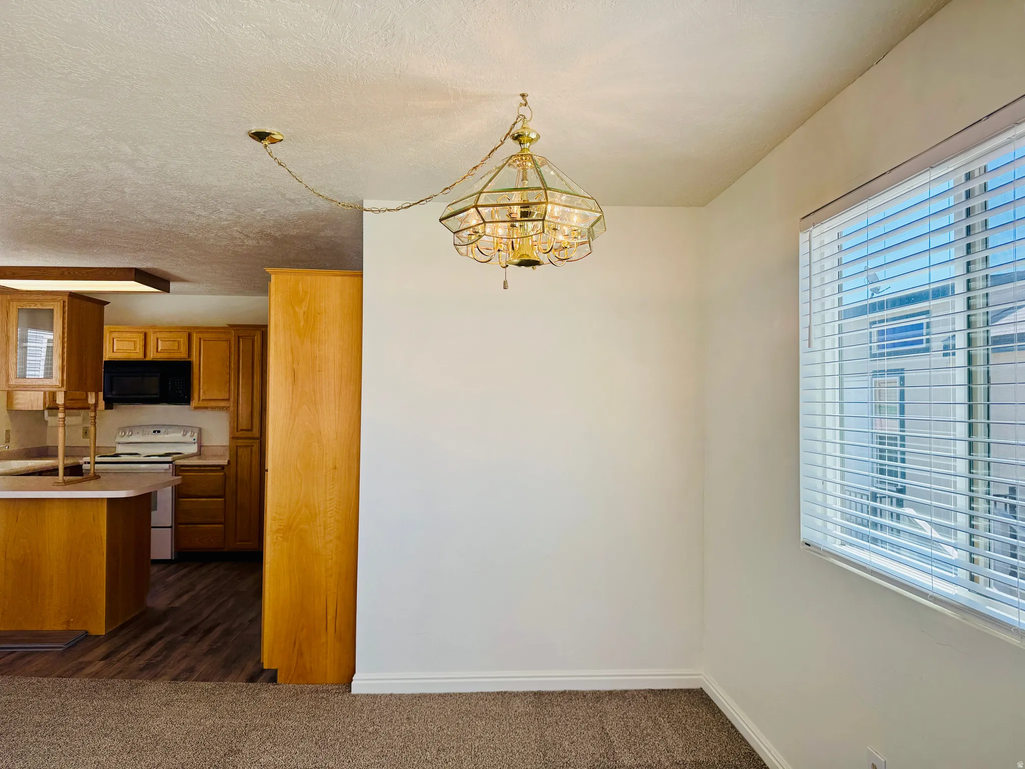 Dining area with an ornate overhead light fixture and a window featuring horizontal blinds