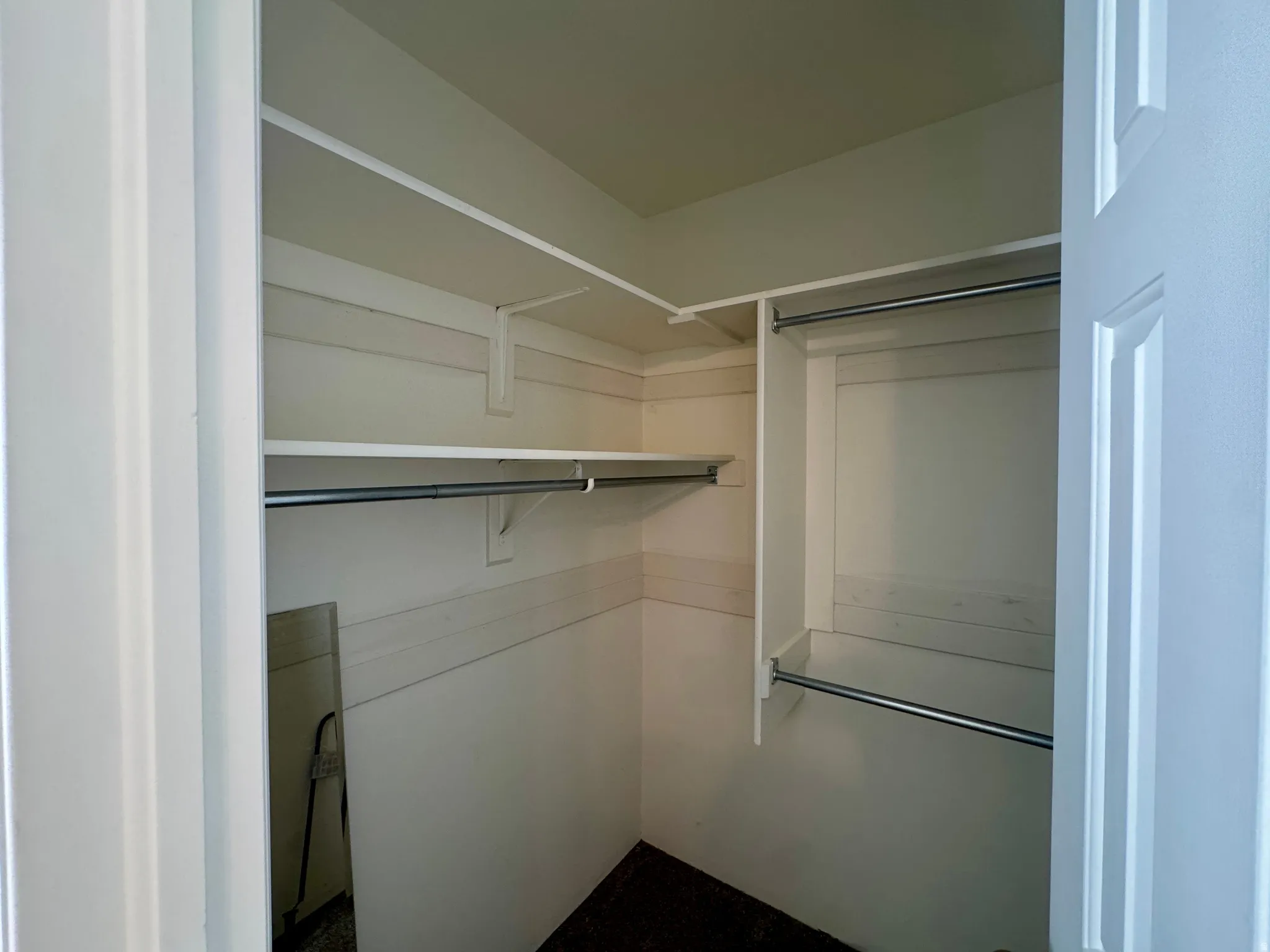 Walk-in closet featuring white shelving and chrome hanging rods