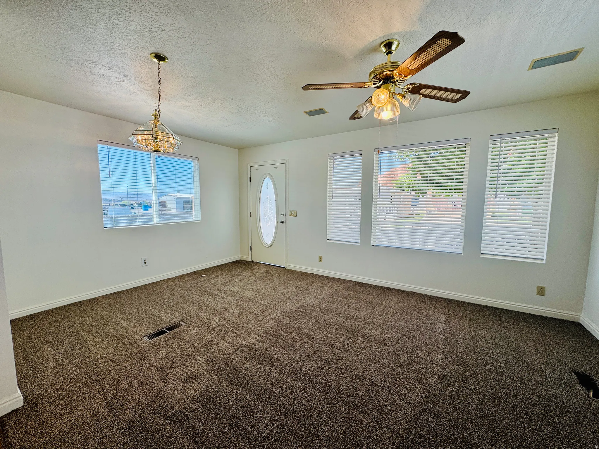 Spacious living area featuring neutral-toned carpet flooring and white painted walls