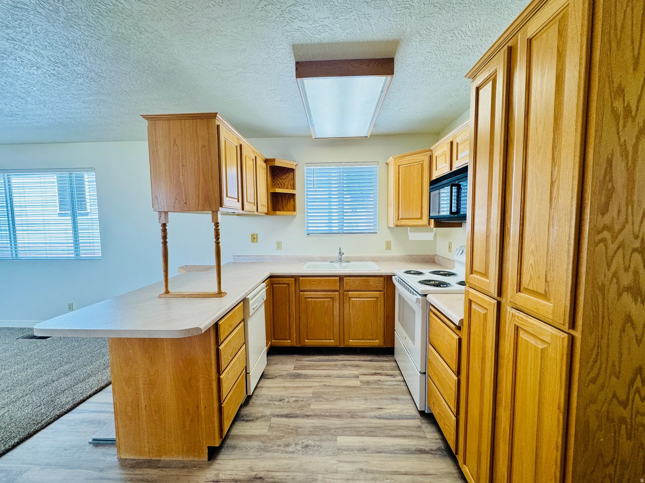 Kitchen featuring wood-finish cabinetry, laminate countertops, and wood-finish flooring