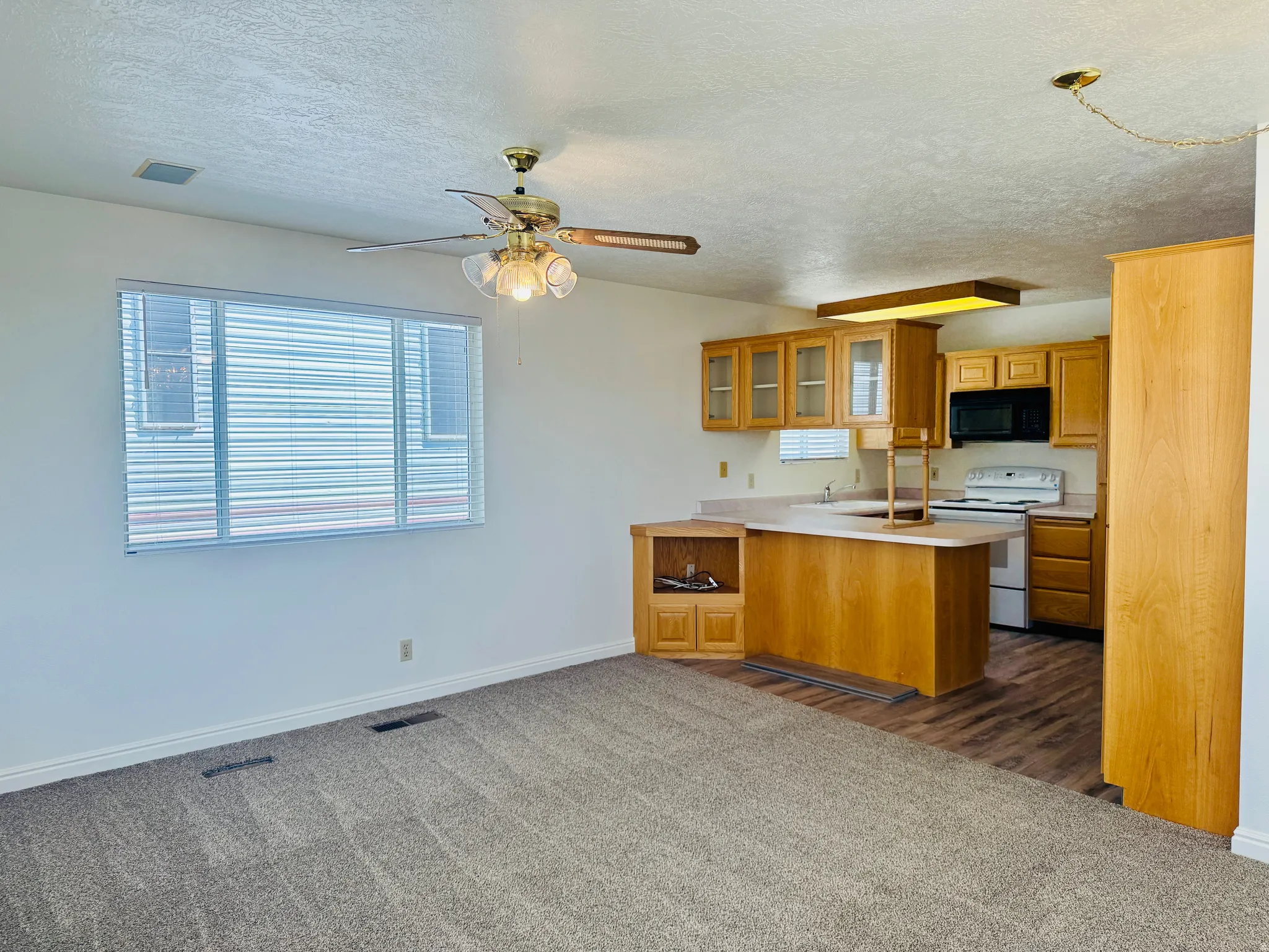 Open-concept living space featuring a kitchen with wood cabinetry, a breakfast bar, and wood-finish flooring