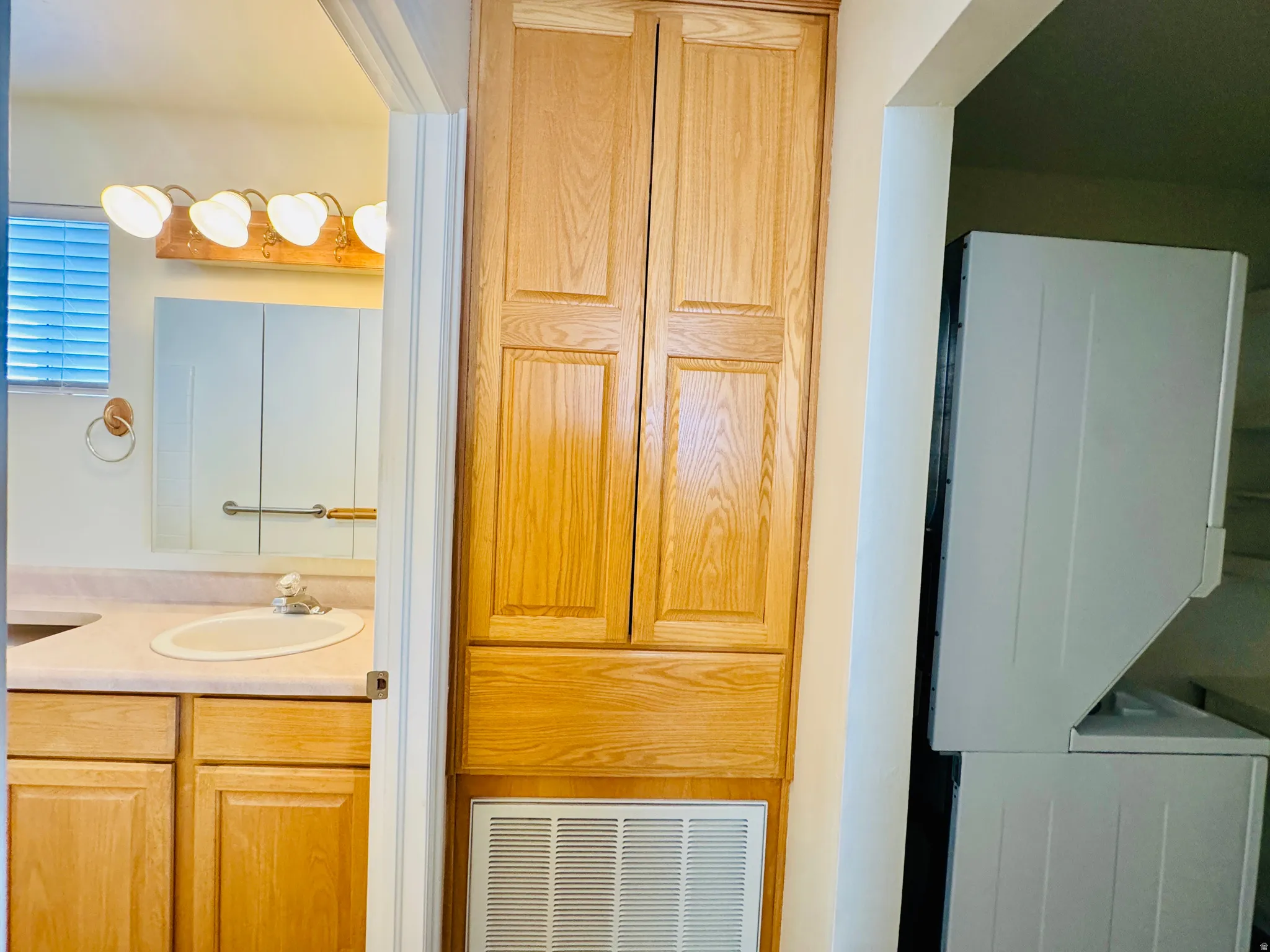 Bathroom vanity with an oval sink, light-toned countertop, and wood-finish cabinetry