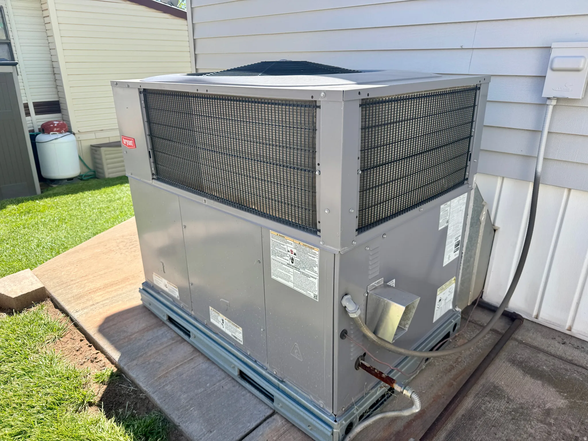 Exterior mechanical system featuring a gray housing unit and black grilles, positioned on a textured concrete pad