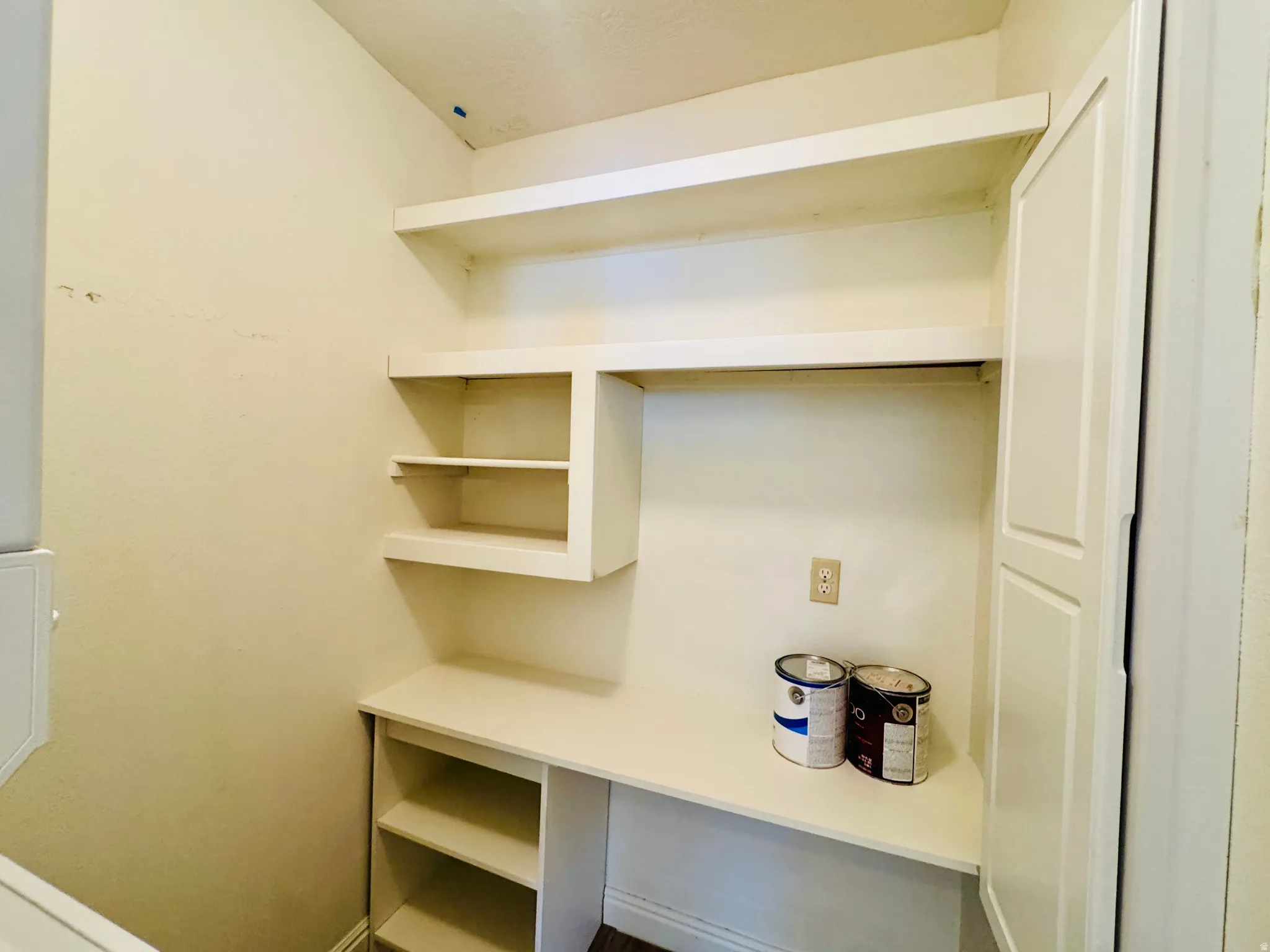 Built-in white shelving unit with open shelves, a desk-height surface, and a tall storage cabinet