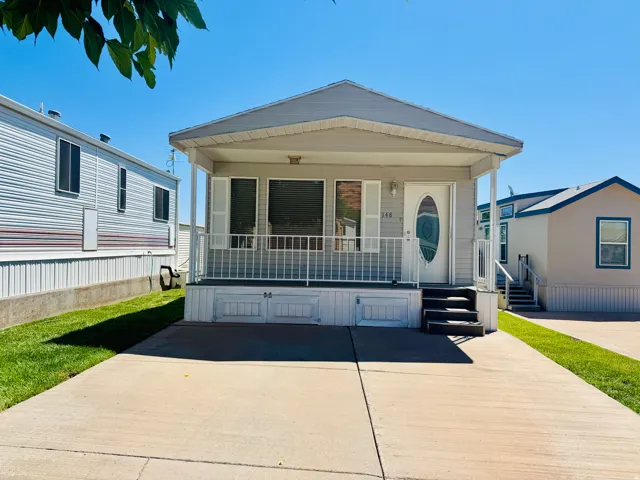Single-story residence featuring a covered front porch with white railing, a white oval glass paneled entry door, and a light gray exterior siding
