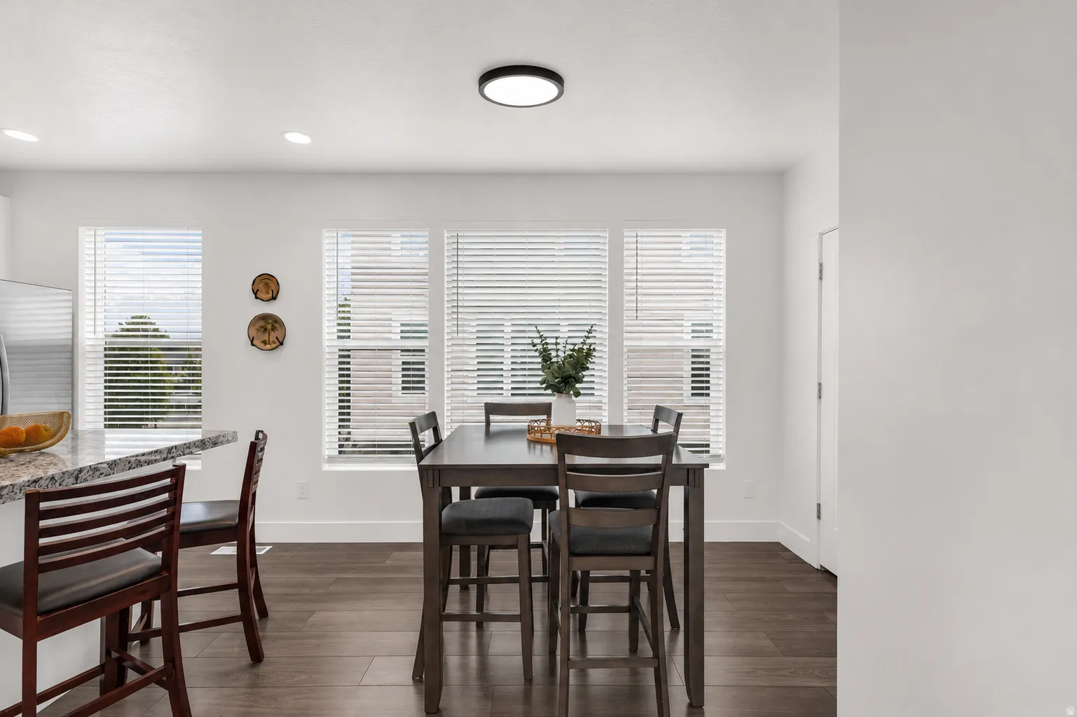 Dining area featuring wood-finish flooring, white walls, and a trio of windows