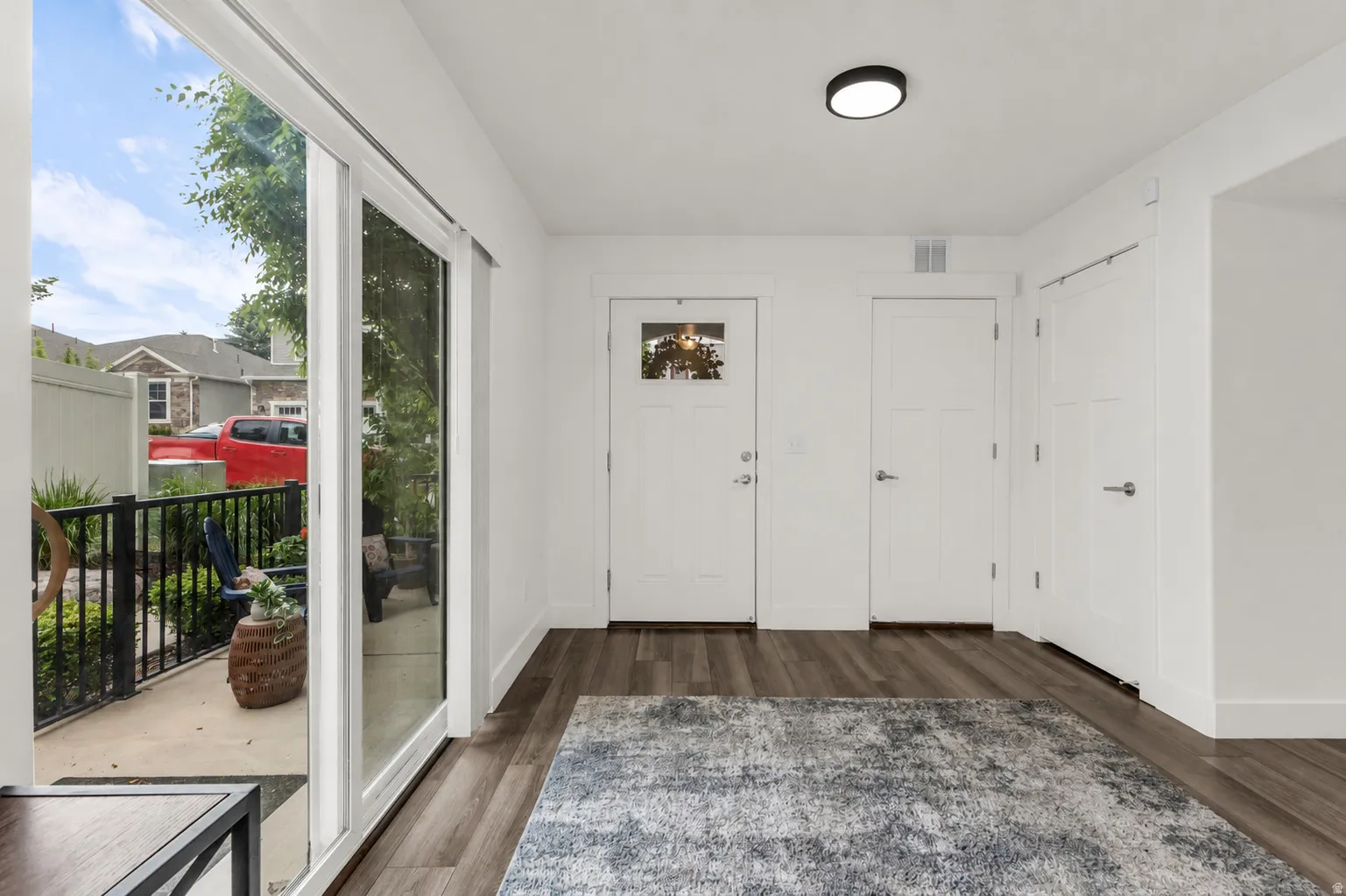 Entryway featuring wood-finish flooring, a white paneled entry door with transom window, and a modern flush-mount ceiling light