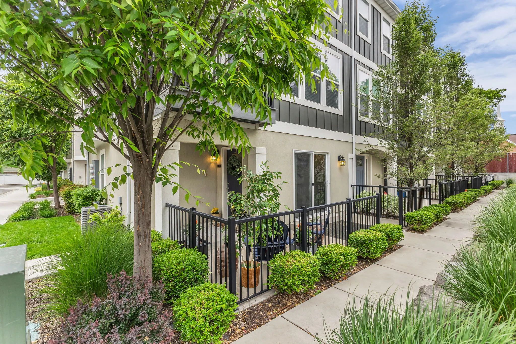 East facing entry, North side patio, featuring  black metal fencing, and a concrete walkway, glass sliding door.