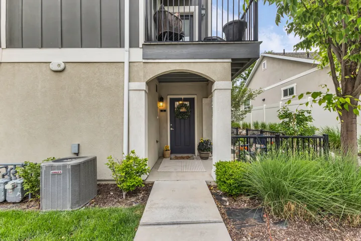 Welcoming arched entryway with a solid door, surrounded by structured landscaping