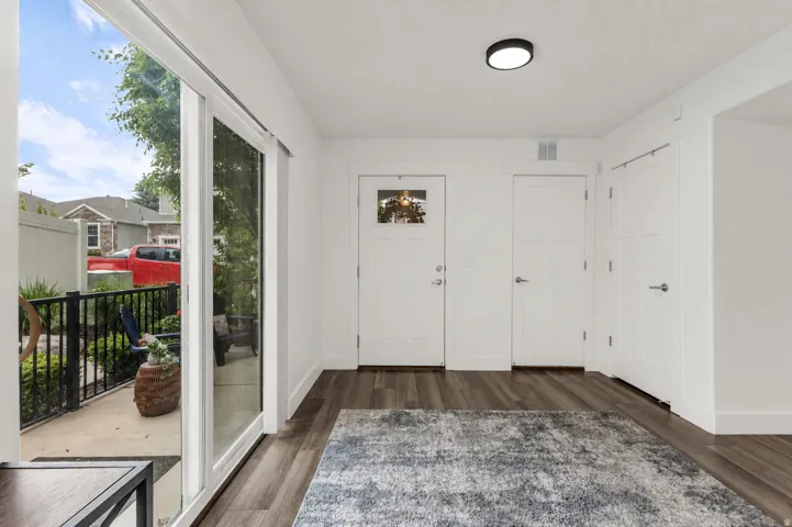 Entryway featuring wood-finish flooring, a white paneled entry door with transom window, and a modern flush-mount ceiling light