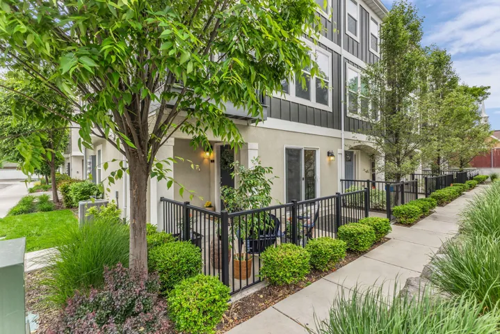 East facing entry, North side patio, featuring  black metal fencing, and a concrete walkway, glass sliding door.
