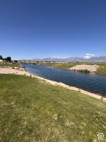 Waterway feature with natural rock banks, expansive green lawn, and distant snow-capped mountains