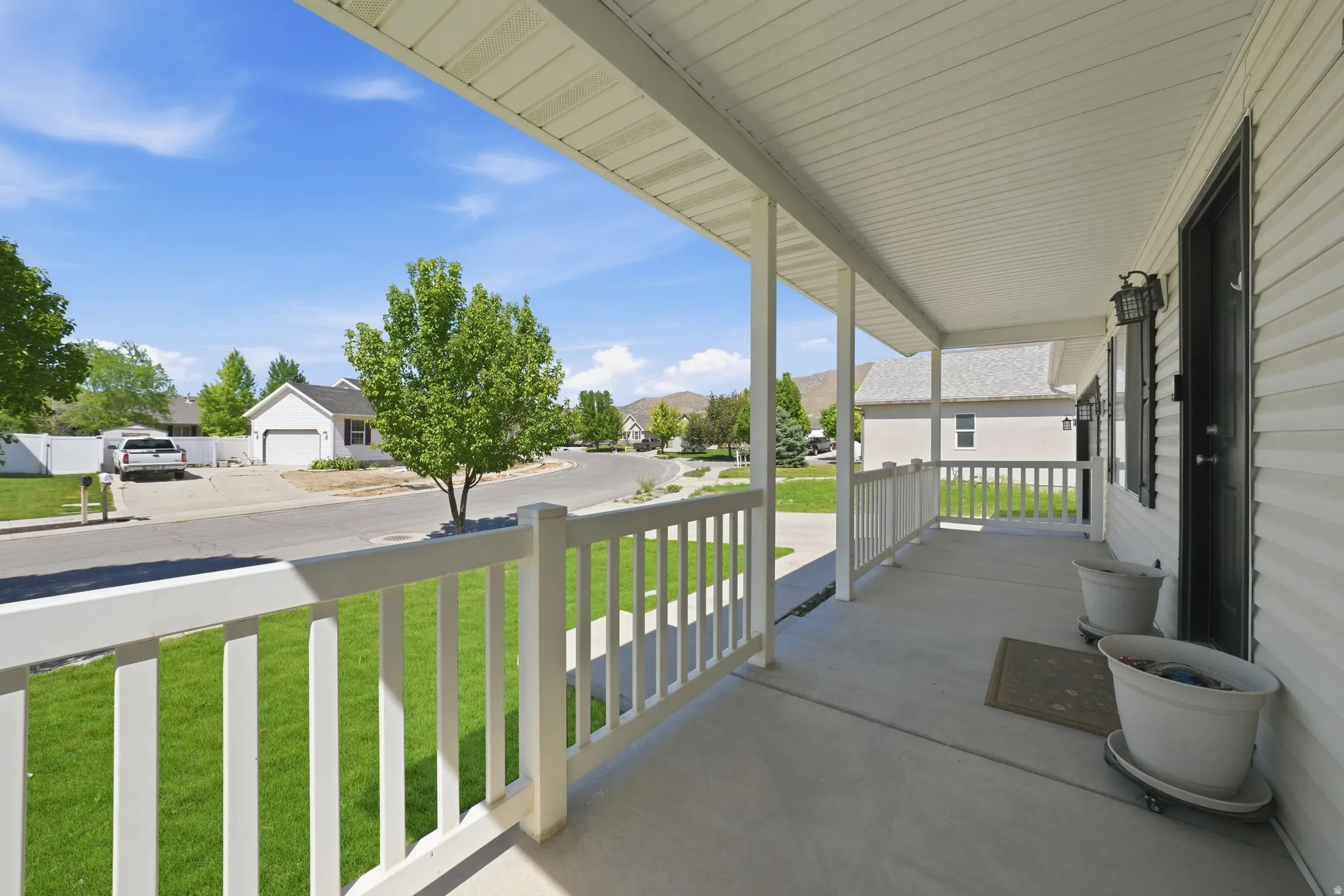Covered front porch featuring white railings, a concrete surface, and white siding