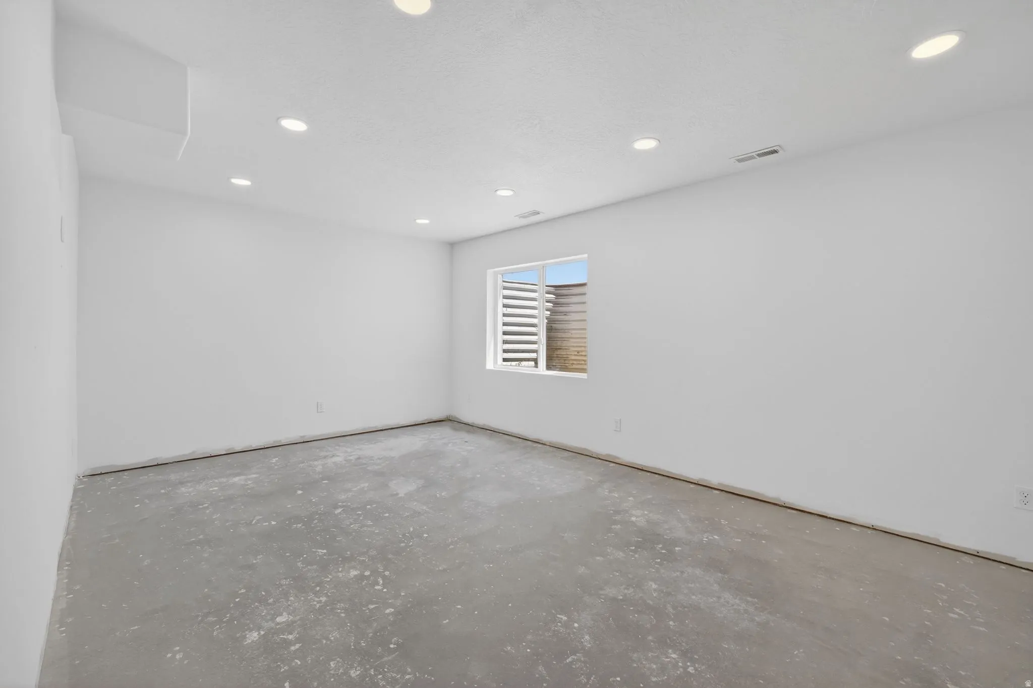 Unfinished room featuring white walls and a concrete floor