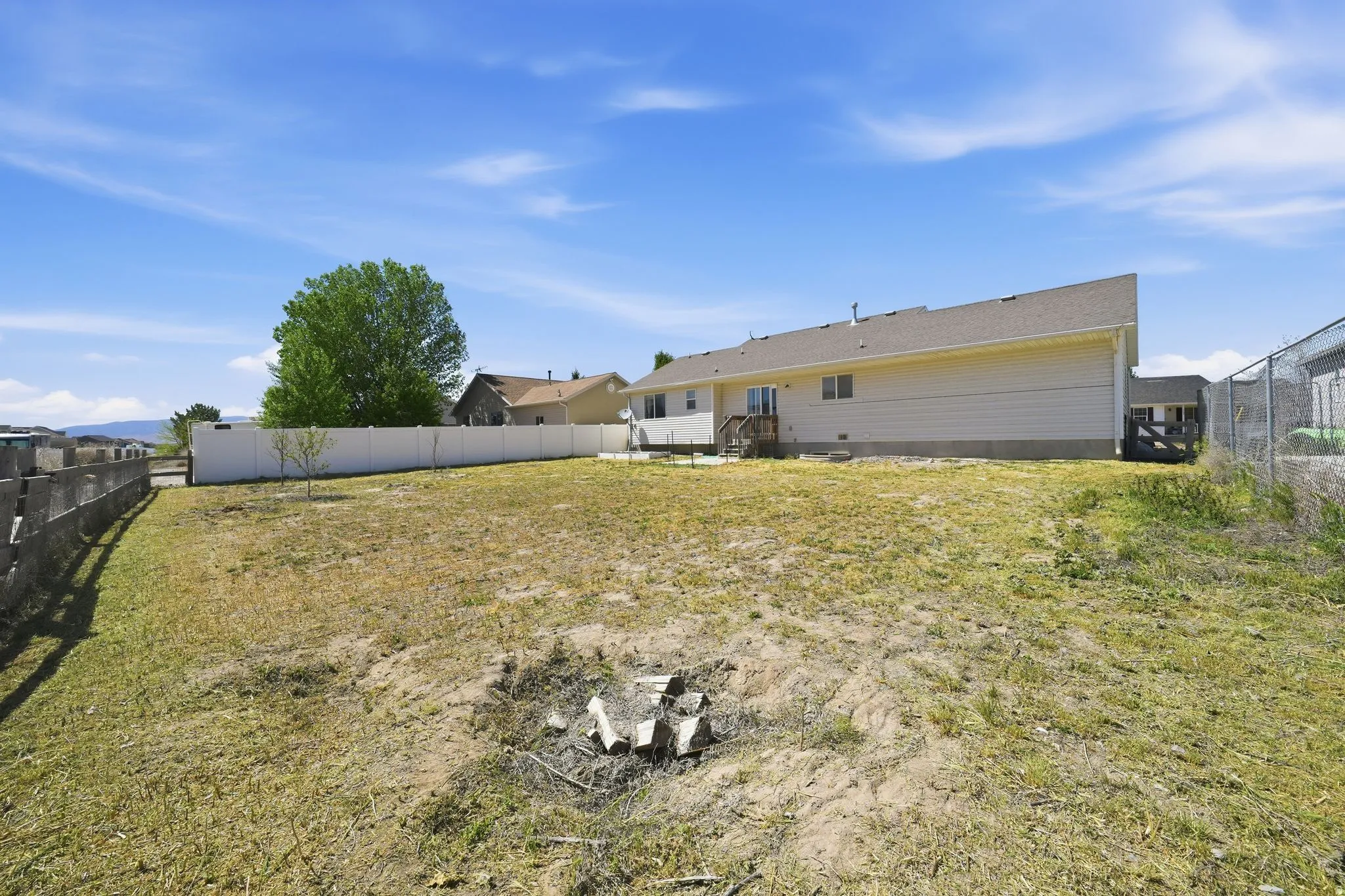 Expansive rear property featuring a vinyl privacy fence, a secondary partial chain link fence, and a mature tree