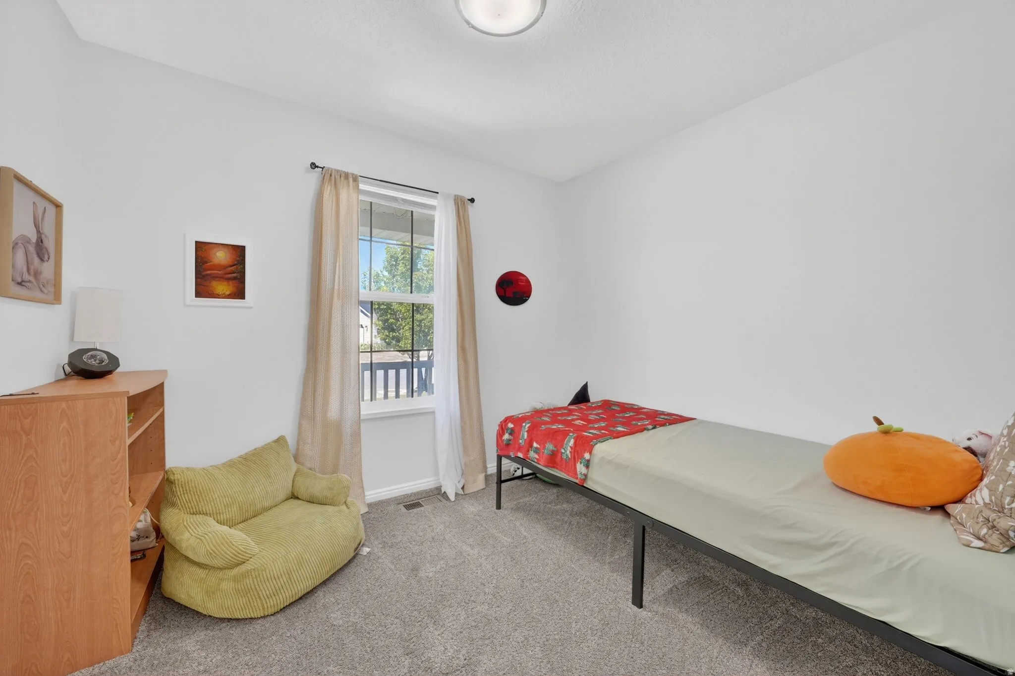 Carpeted room with a double-pane window, flush-mount ceiling light, white walls, and a wooden bookshelf