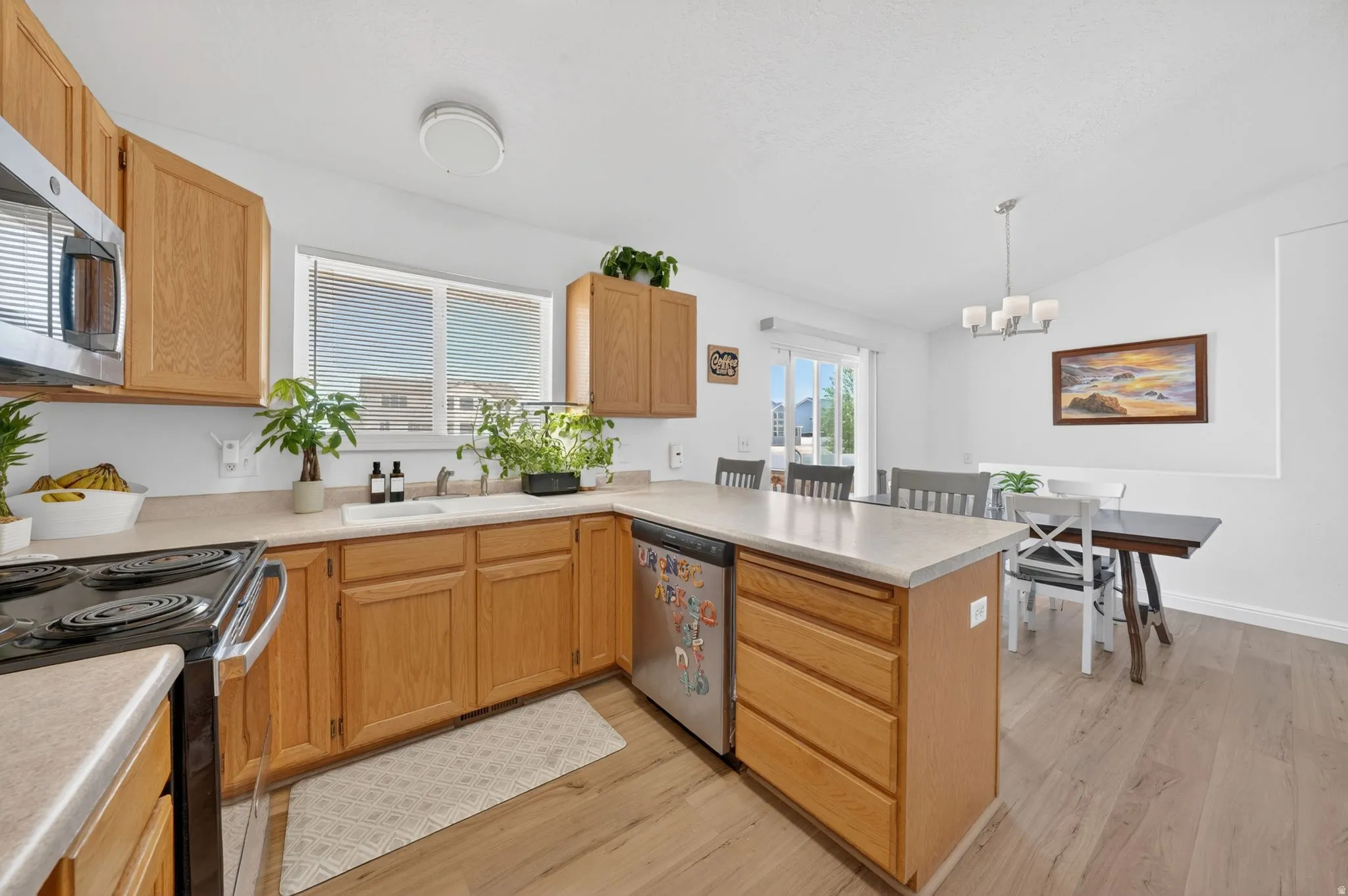 Kitchen featuring light wood cabinetry, light-toned countertops, stainless steel appliances, and wood-finish flooring