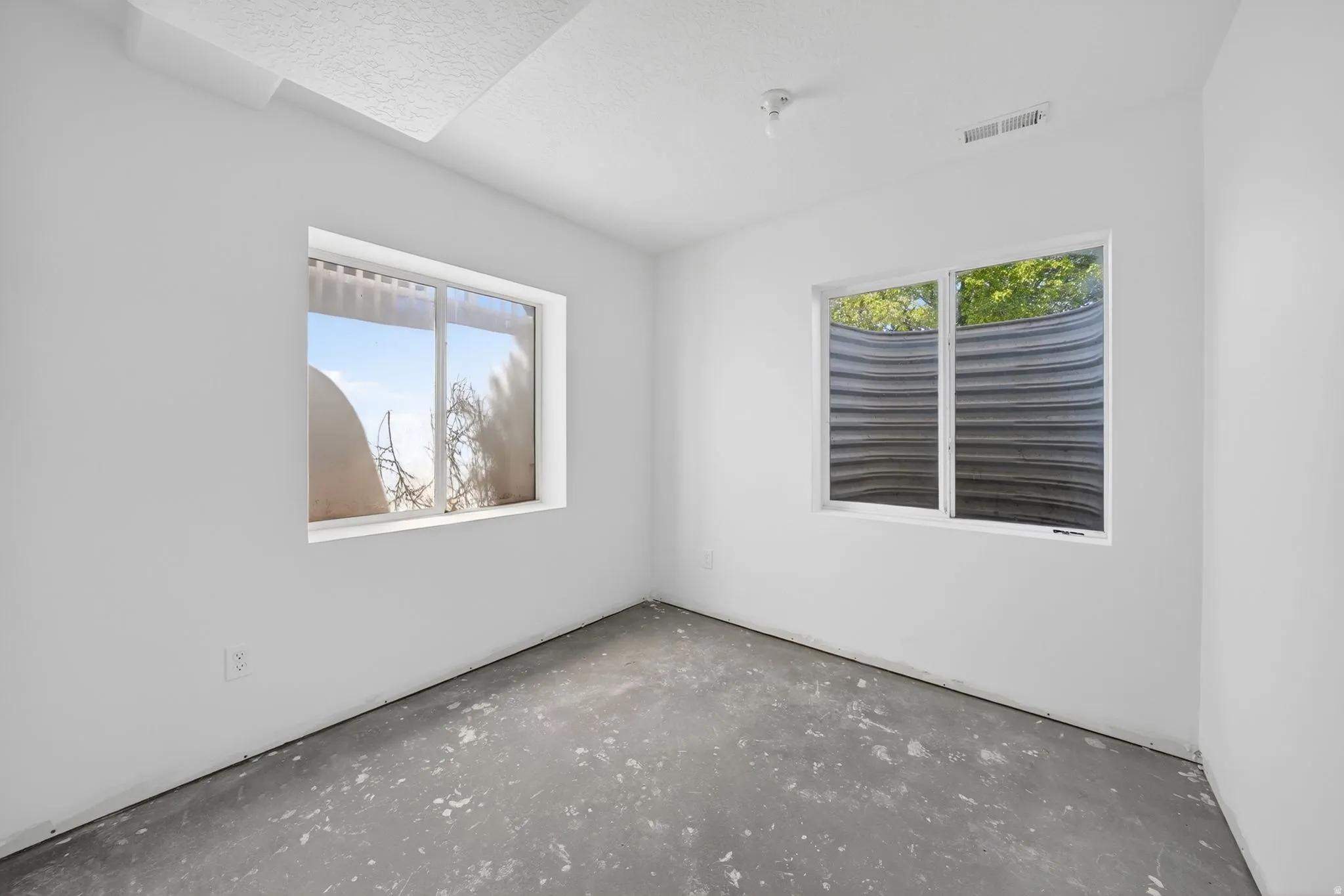 Room featuring two windows, clean white walls, and a concrete floor