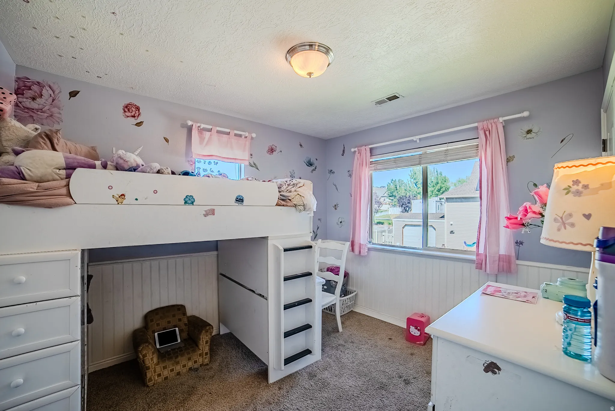 Carpeted room featuring a window with blinds and pink drapes, white wainscoting, and a white built-in loft bed with integrated drawers and a ladder