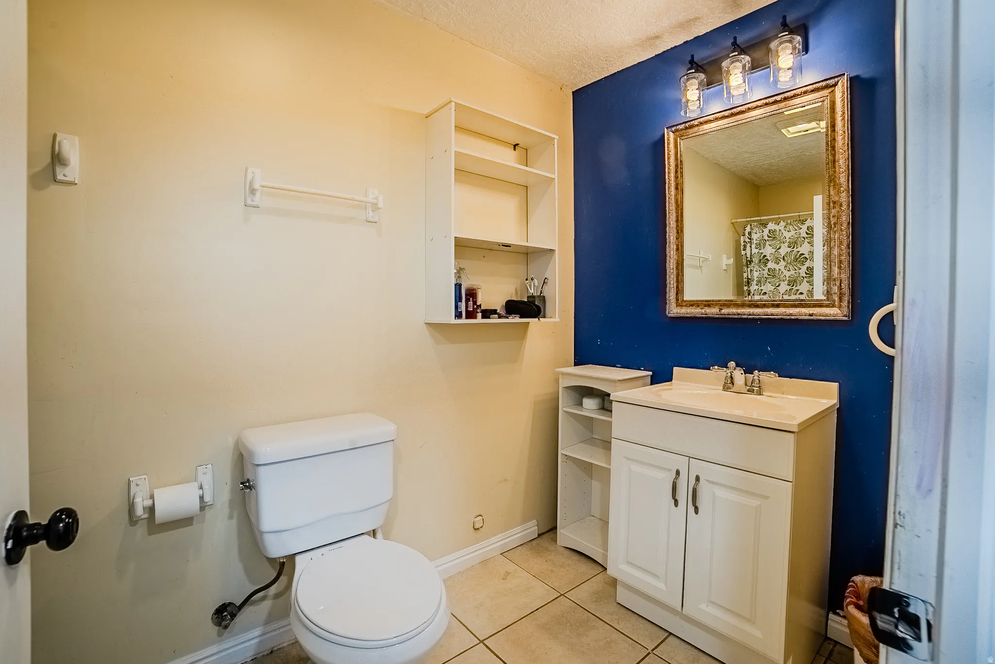 Bathroom featuring a single vanity with built-in cabinetry, an ornate framed mirror, and a three-light fixture