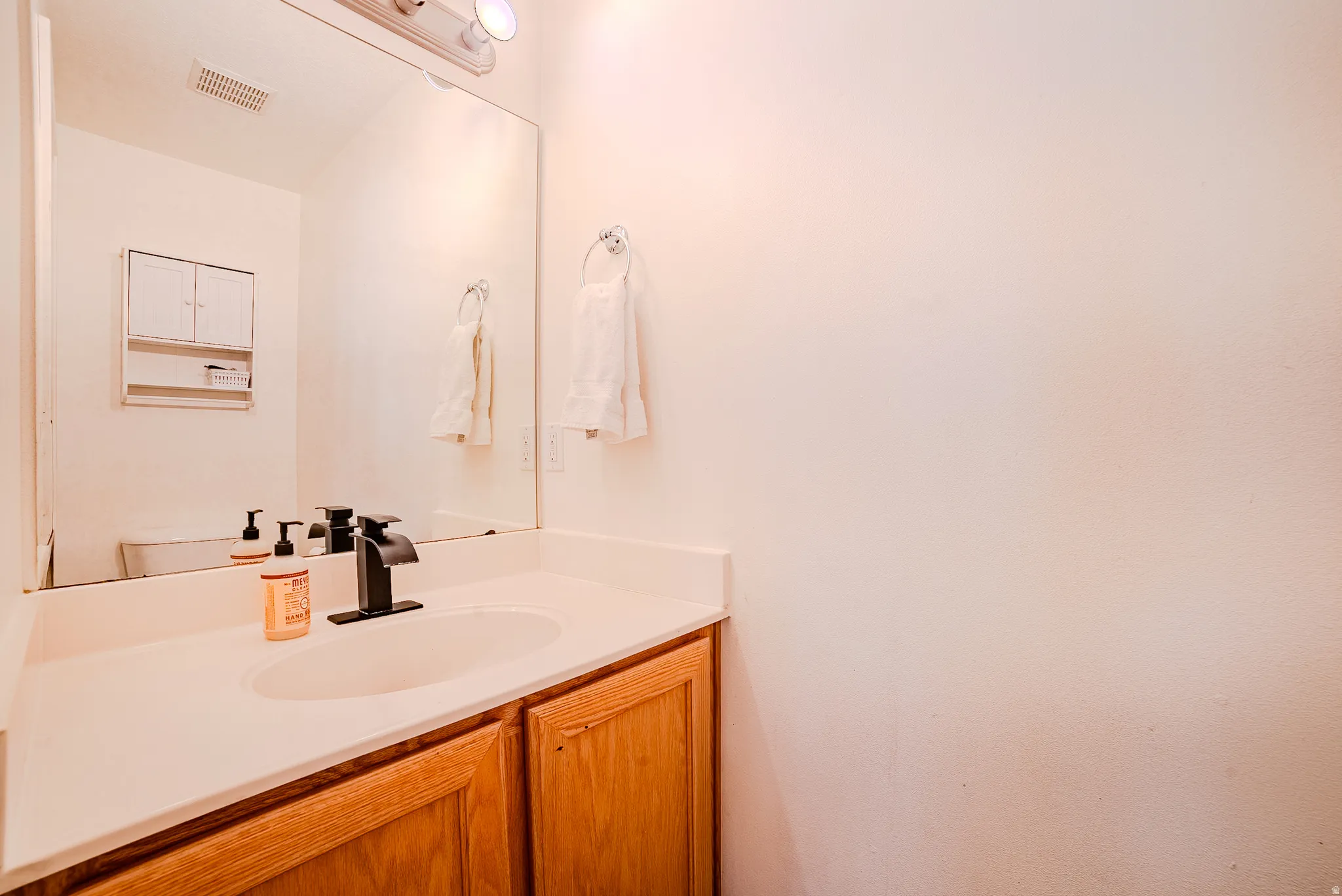 Bathroom vanity featuring a white countertop, oval sink, and a matte black faucet