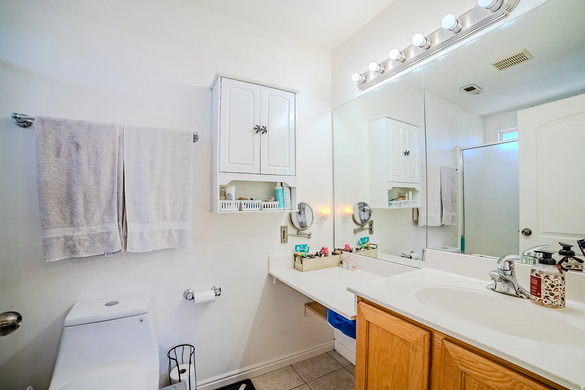 Bathroom featuring a dual-sink vanity with wood-finish cabinetry and a white countertop