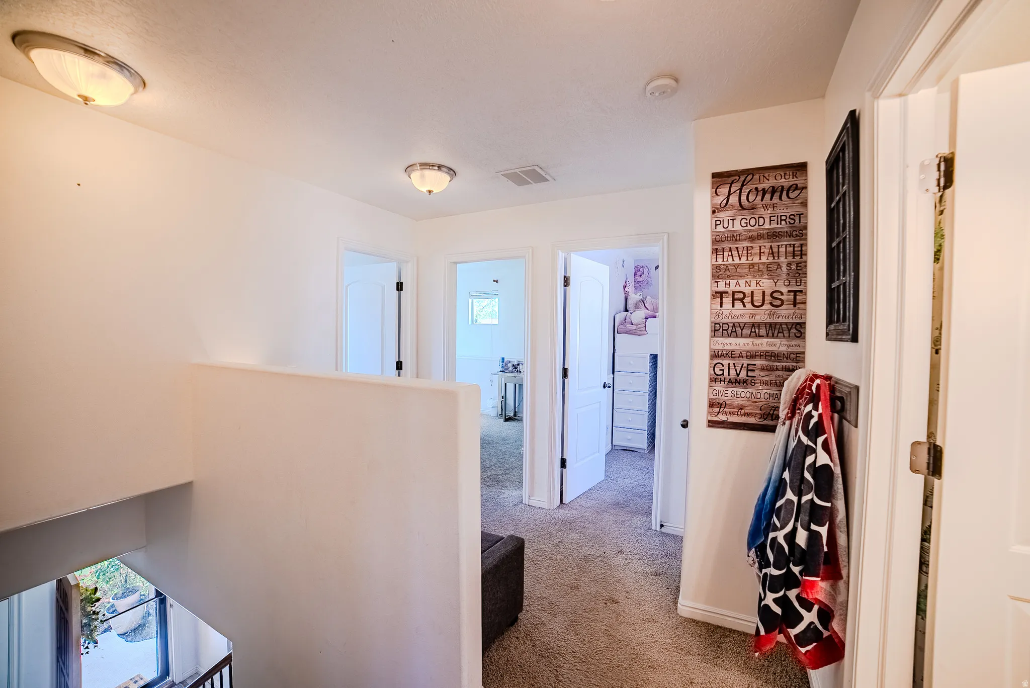 Carpeted hallway with white walls and trim, featuring flush-mount ceiling lights and multiple interior doors