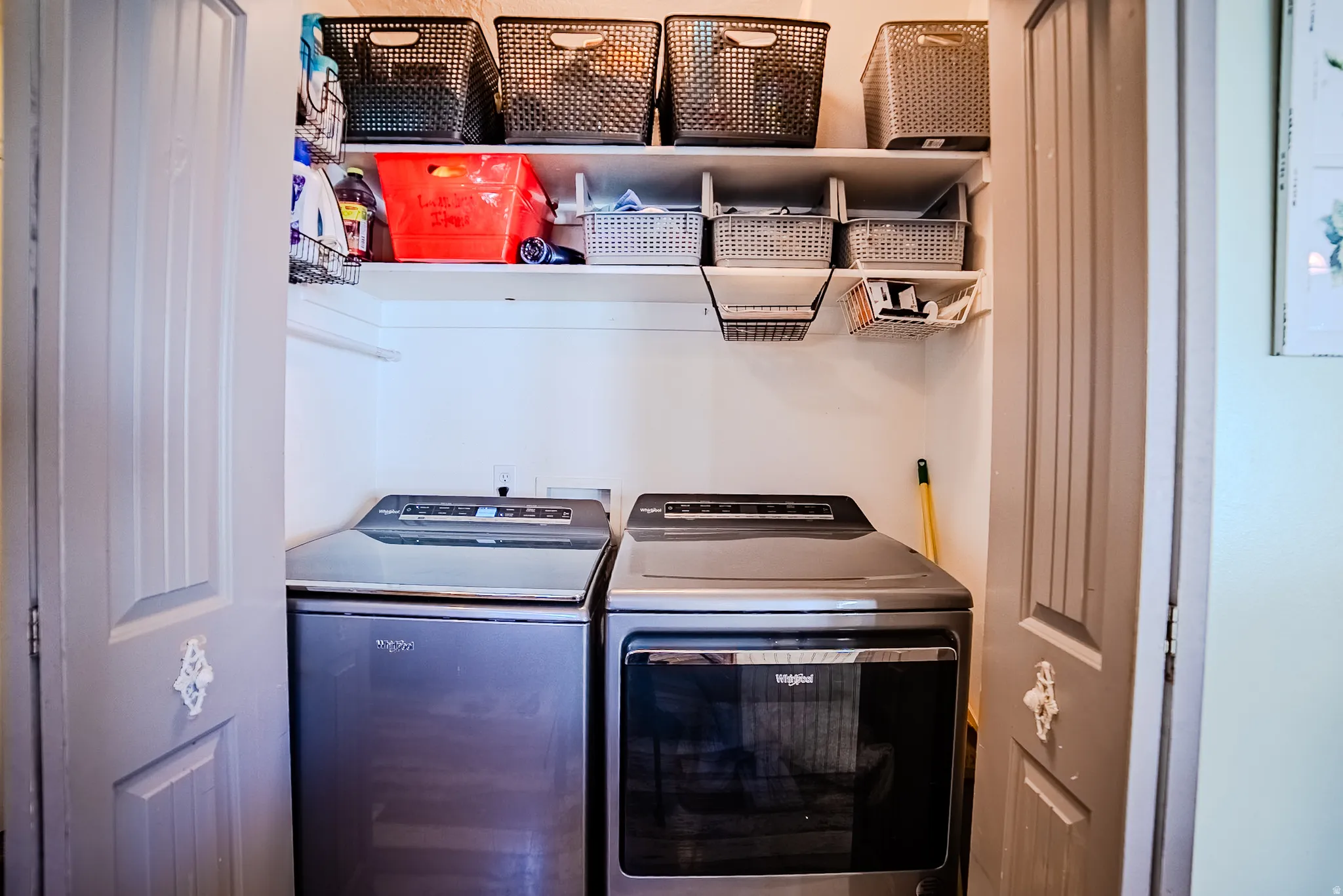 Dedicated laundry area featuring a washer and dryer, integrated shelving, and wall-mounted storage baskets