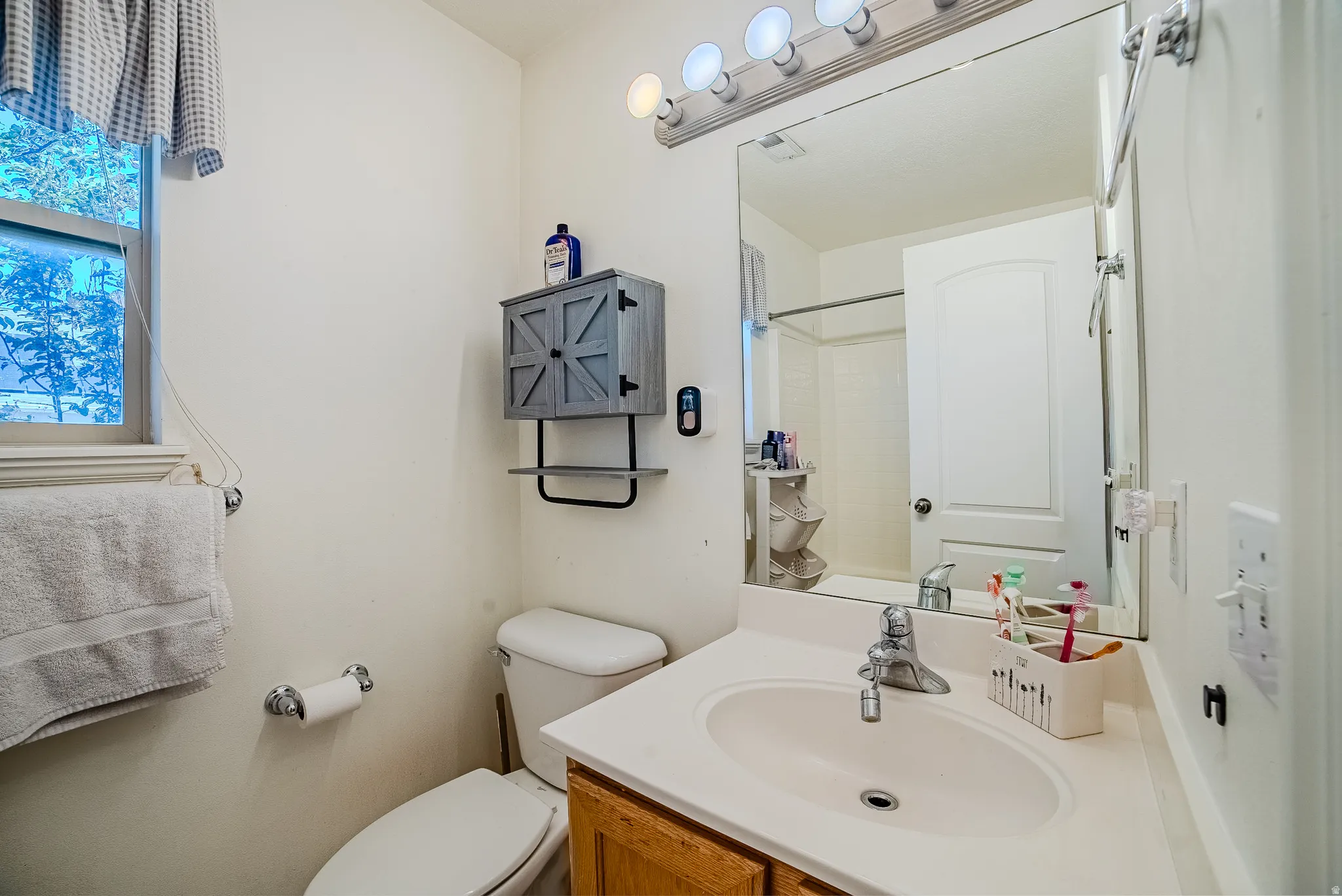 Bathroom featuring a single vanity with a laminate countertop, an oval undermount sink, and a chrome faucet