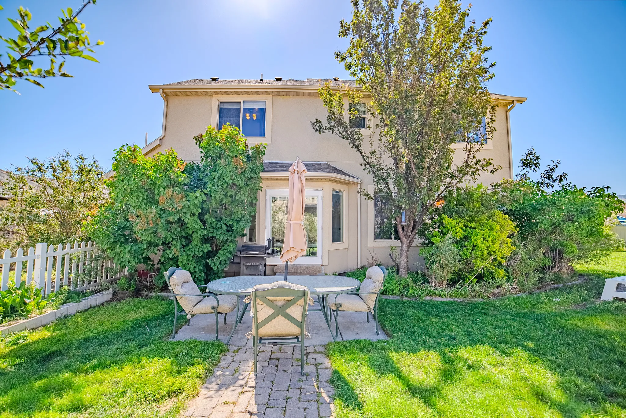 Expansive backyard featuring a manicured lawn, picket fencing, and mature trees